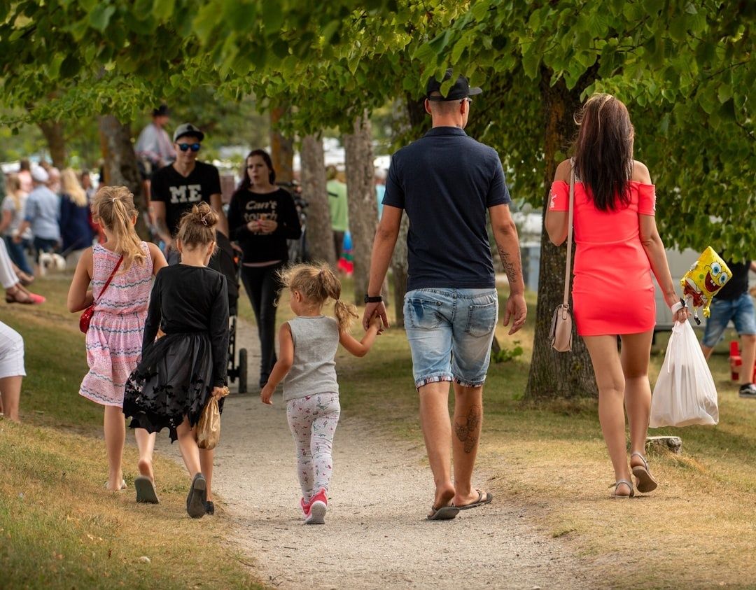Familjer promenerar bland träd i en livlig sommarpark